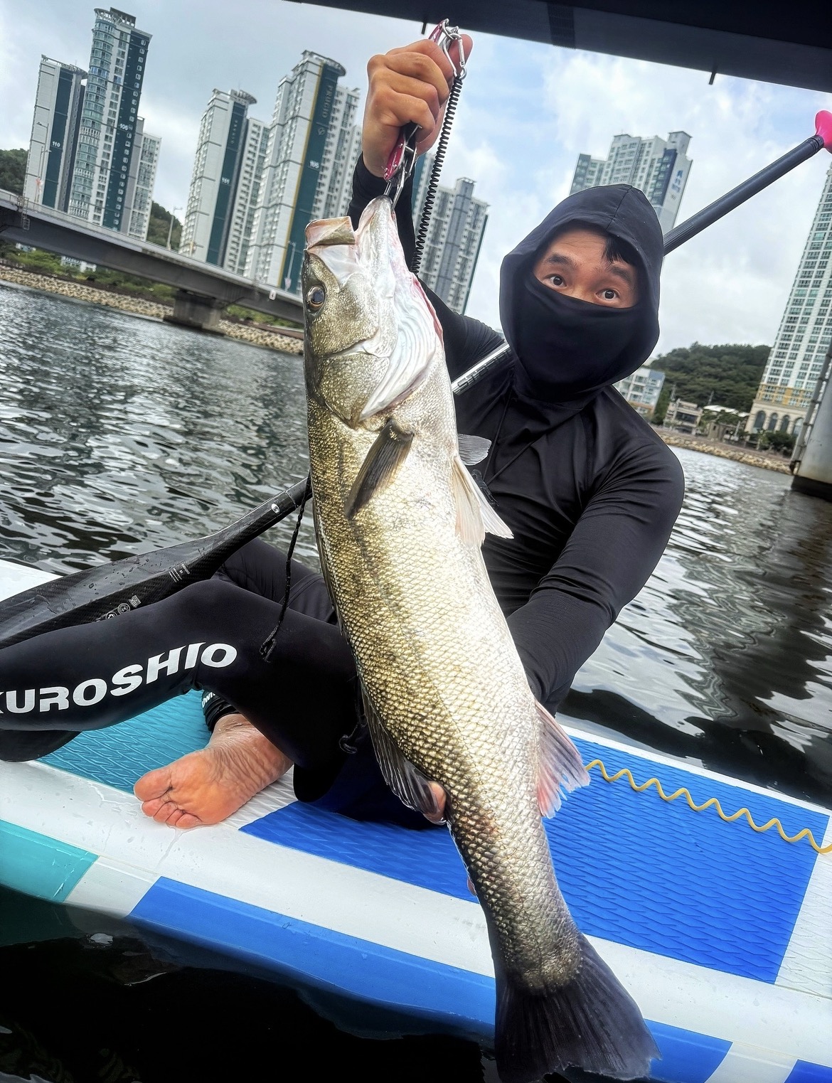 Ahn Sugon holding a sea bass on his SUP board