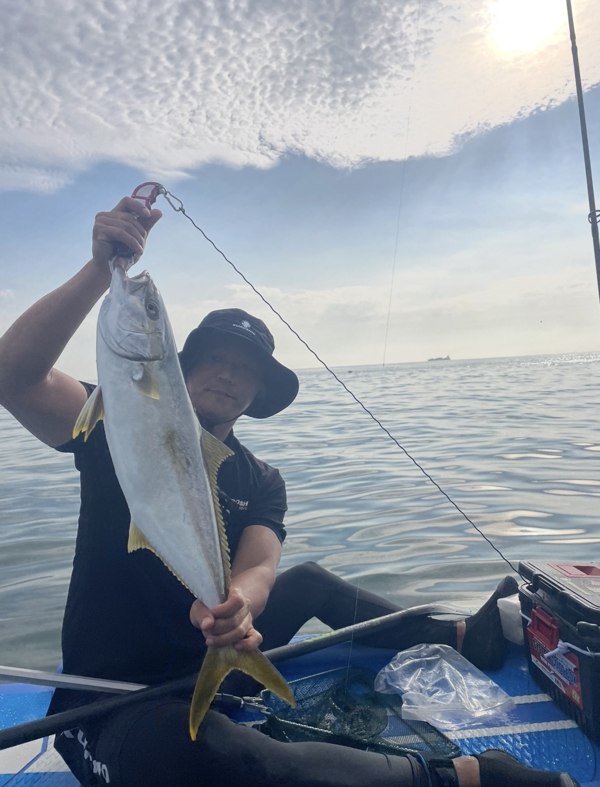 Ahn Sugon holding a freshly caught fish on a SUP board