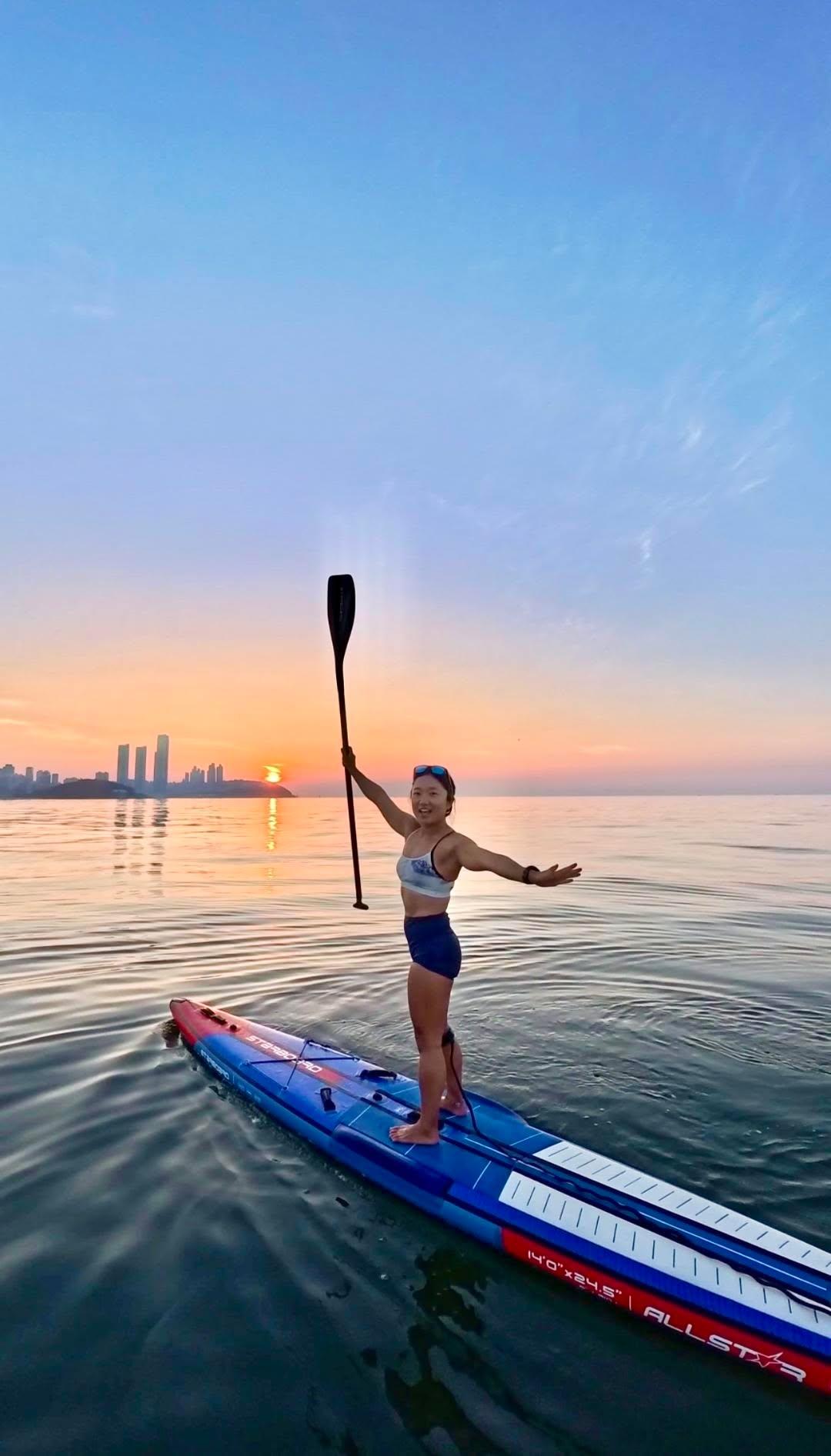 Bae Soyeong (Haebom) paddleboarding on sunlit water